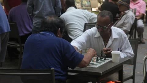 Two senior men playing a game of chess at an outdoor table Stock Footage 341323460