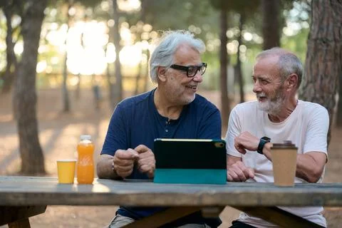 Two senior men using tablet and talking in park Stock Photos