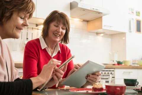 Two senior women using smart phone and digital tablet in kitchen, Munich, Stock Photos