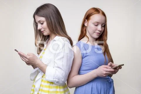 Two serious beautiful young women texting on smartphones Stock Photos
