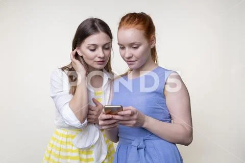 Two serious pretty young women using smartphone Stock Photos