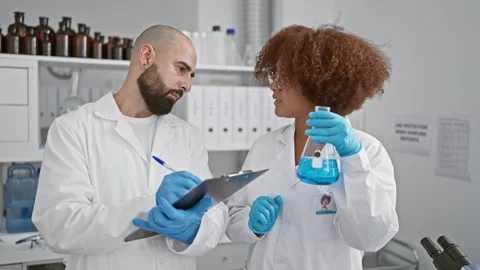 Two serious scientists writing analysis results on clipboard, working toget.. Stock Footage 262753848