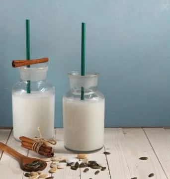Two serving bottles of vegetable milk made from pumpkin seeds on a blue Stock Photos