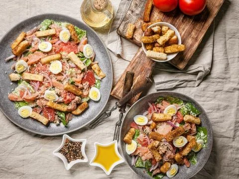 Two servings of Caesar salad with red fish, romaine lettuce, quail eggs and g Stock Photos