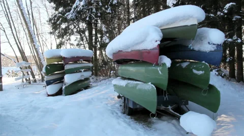 Two sets of boats piled upside down with snow Stock Footage