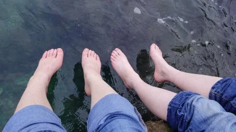 Two sets of feet dangling over the sea, Croatia Stock Photos