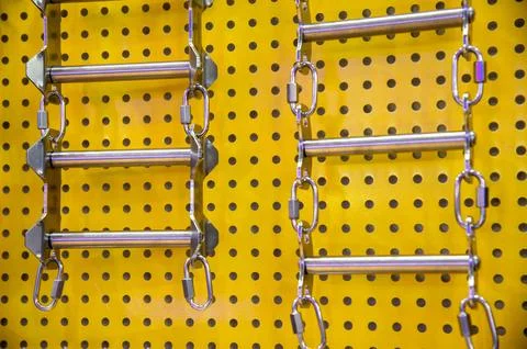 Two sets of metal bars with chains hanging from a yellow wall Stock Photos