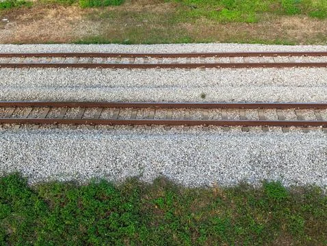Two sets of parallel train tracks run across a bed of light gray gravel, bord Fotos Stock