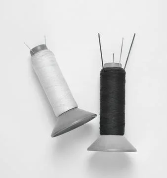 Two sewing pins with spools of white and black thread Foto stock