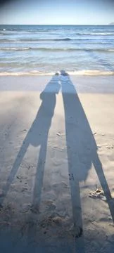 Two shadows on a sandy beach by the sea Stock Photos