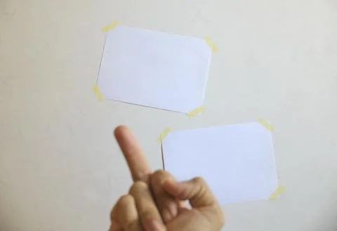 Two sheets of notes on the wall in front of which is a hand with a gesture of Foto stock