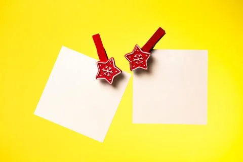 Two sheets of white paper pinned with a Christmas clothespin yellow backgroun Stock Photos