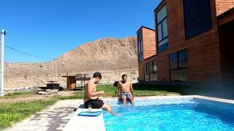 Two shirtless friends having a conversation sitting on the edge of a mountain ba Stock Footage 199554539