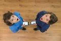 The two shocked twin stand with a phone. View from above Photo