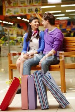 Two shopaholics chatting after shopping with focus on their paperbags on the flo Stock Photos