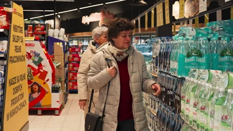 Two Shoppers Are Checking Bottled Water on a Shelf Inside the Netto Supermarket Stock Footage 325946690