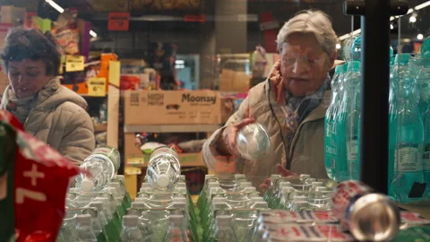 Two Shoppers Examine Bottled Water on a Display Inside the Netto Supermarket in Stock Footage 325946993