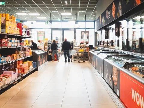 Two shoppers navigating the aisle of a modern Italian grocery store pushing.. Stock Photos