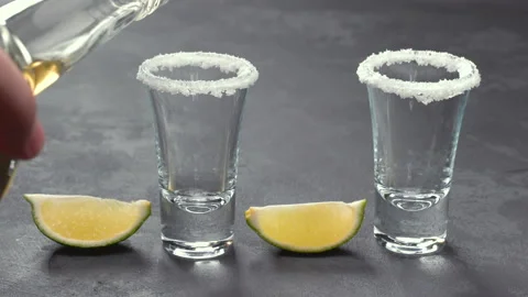 Two shot of  cold gold  tequila a black wooden background Stock Footage 98971492