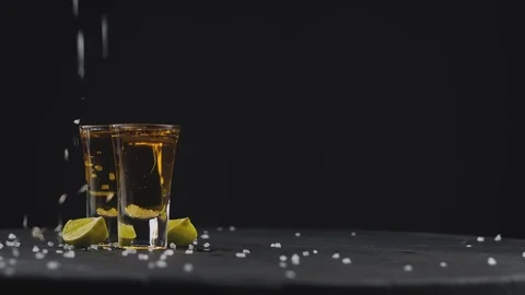 Two shot with golden tequila on a black background on a rotating black board Stock Footage 120194049