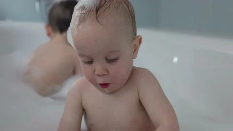Two sibling brothers take bath together having fun with soap foam playing water 库存影片 218850897