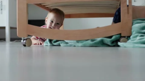 Two siblings brothers playing floor bedroom climb under bed crawl under crib in Stock-Footage 217459859