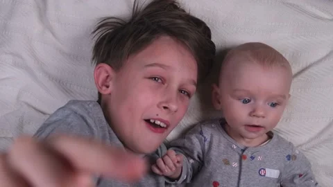 Two siblings brothers , small and large, older and younger lie playing and Stock Footage 232223196