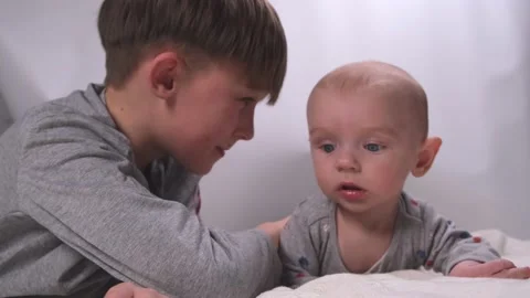 Two siblings brothers , small and large, older and younger lie playing and Stock Footage 233375738