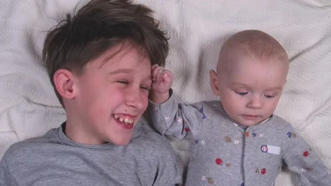 Two siblings brothers , small and large, older and younger lie playing and Stock Footage 237218348