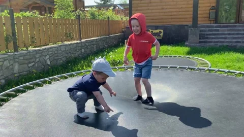 Two siblings jumping on a trampoline and playing in the summer.  Stock Footage 131821959