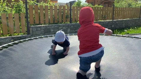 Two siblings jumping on a trampoline and playing in the summer.  Stock Footage 131821978