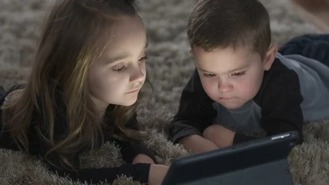 Two siblings laying on the ground watch movie on tablet Stock Footage 85366716