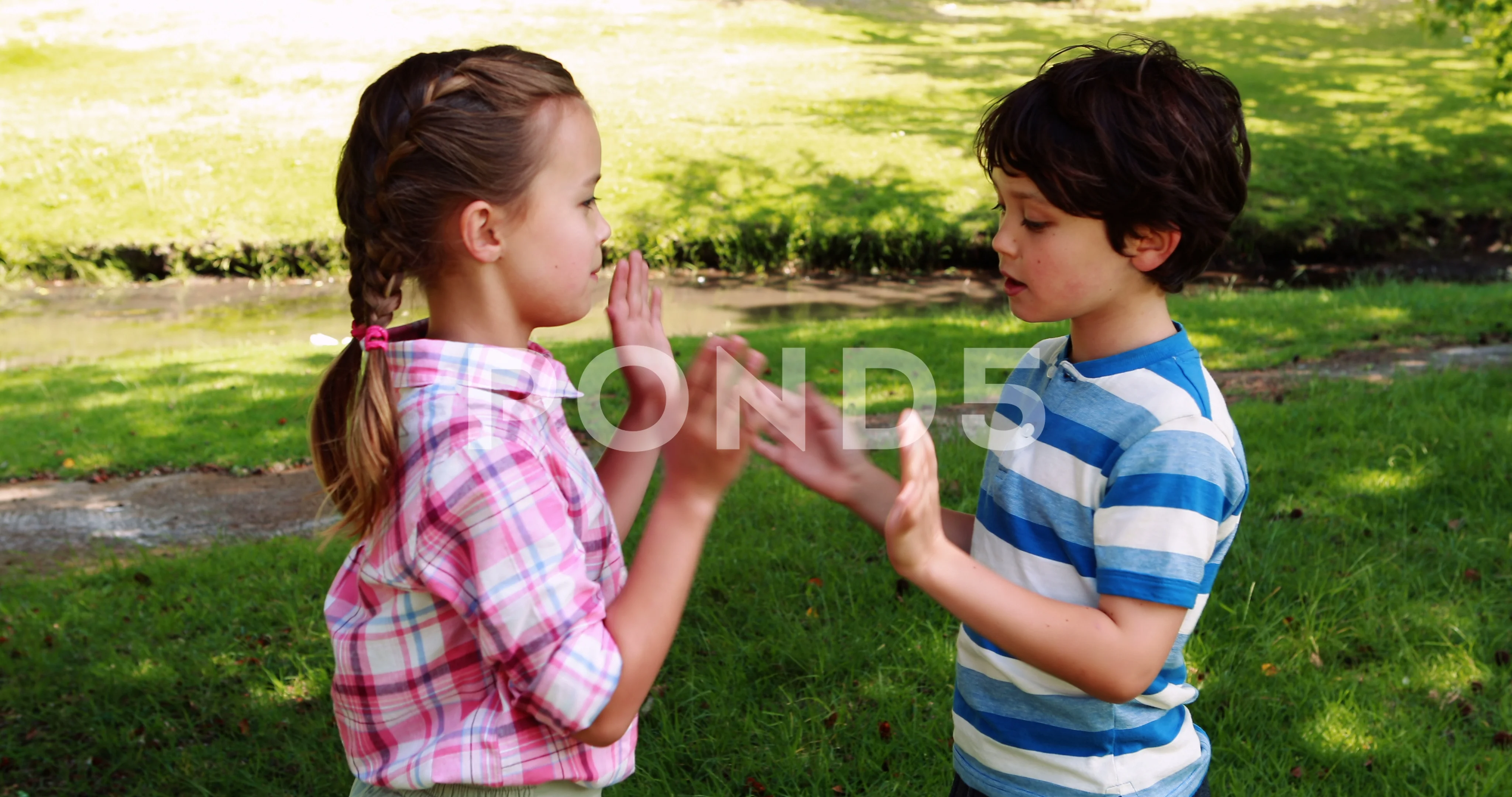 Two siblings playing clapping game in park