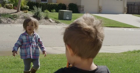 Two siblings, playing together spraying water in the yard, shot on RED EPIC Stock Footage 105376350