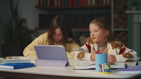 Two siblings study together at home, writing in notebooks and using a tablet Stock Footage 343423411