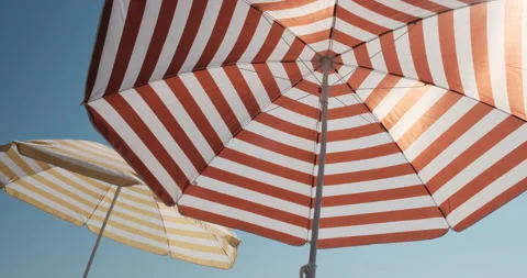Two side by side striped umbrellas on a beach on a sunny perfect chilling day. Stock-Footage 142999238