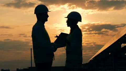 Two silhouette of engineers are having a conversation on a rooftop during sunset Stock Footage 98133714
