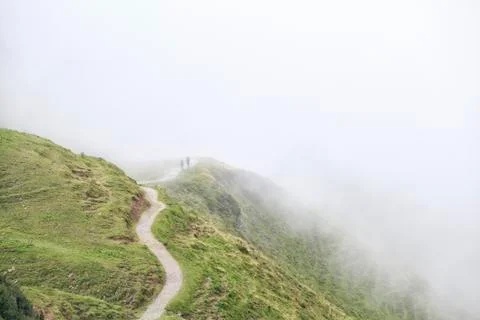 Two silhouettes walking on mountain path in fog Stock Photos