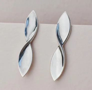 Two silver earrings on a white background. Close-up. Stock Photos