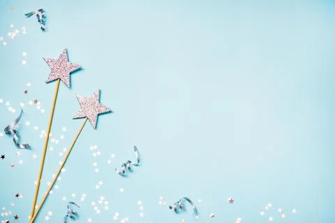Two silver party magic wands, sequins and ribbons on a blue background. Cop.. Stock Photos