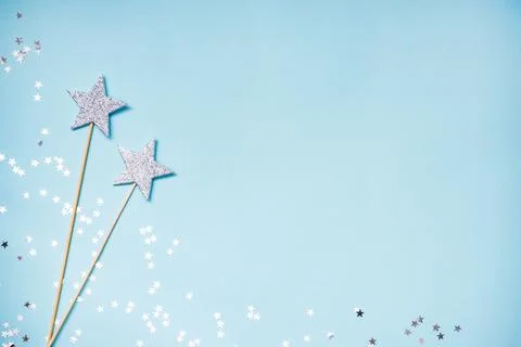 Two silver party magic wands and scattered sequins on a blue background. Co.. Stock Photos