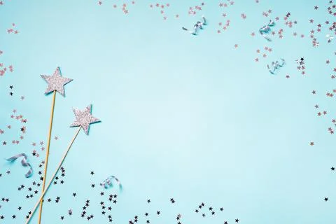 Two silver party magic wands, sequins and ribbons on a blue background. Cop.. Stock Photos