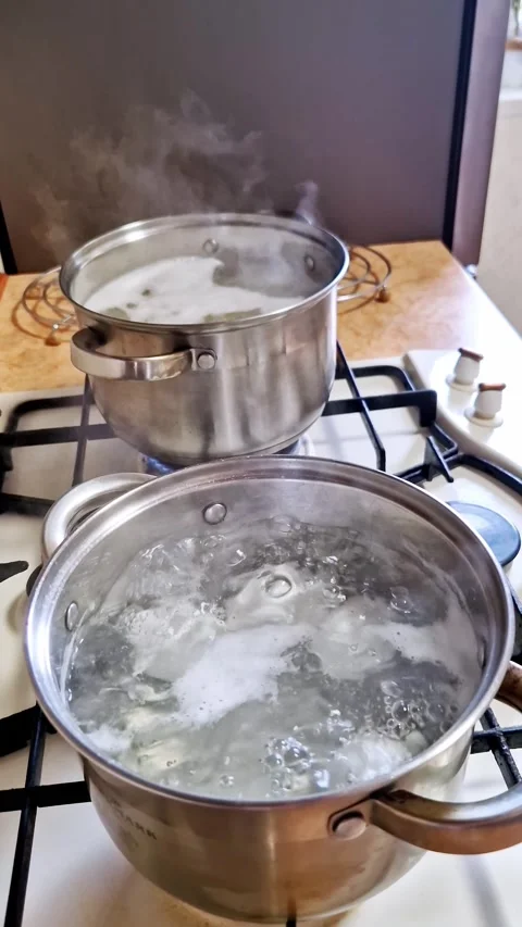 Two Silver Pots of Boiling Water on a Gas Stove Video stock 321964350