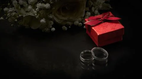 Two silver rings, a red gift box lie on a dark background. Close-up. Selectiv Stock Photos