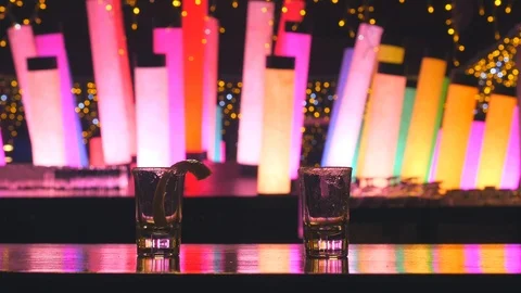 Two silver tequila shots with lime drunk on bar counter with color changing led Stock Footage 106395975