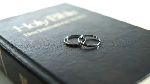 Two silver wedding rings on bible cover Stock Footage 128669797