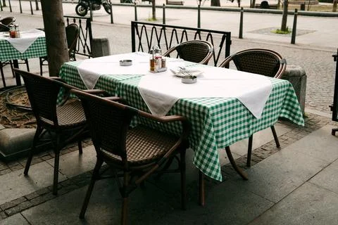 Two simple cafe tables by the sidewalk, framed by trees and iron railing, whe 写真素材