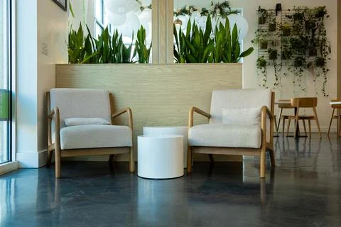 Two simple chairs in a bright space with plants at a modern indoor cafe in .. Stock Photos