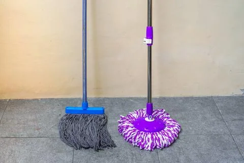 Two simple, modern floor mops leaned against the wall Stock Photos