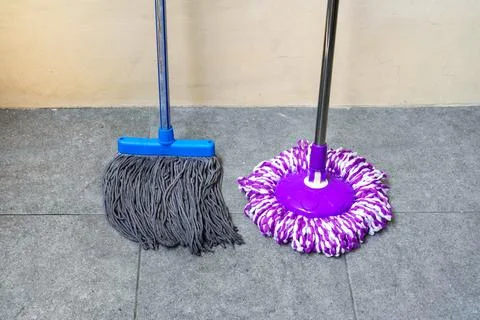 Two simple, modern floor mops leaned against the wall Stock Photos